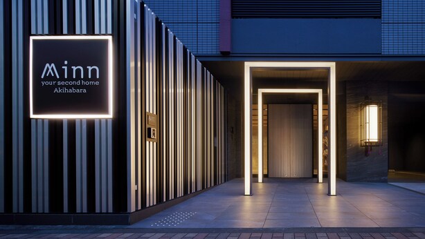 A modern building entrance with a lit sign reading "Minn your second home Akihabara."