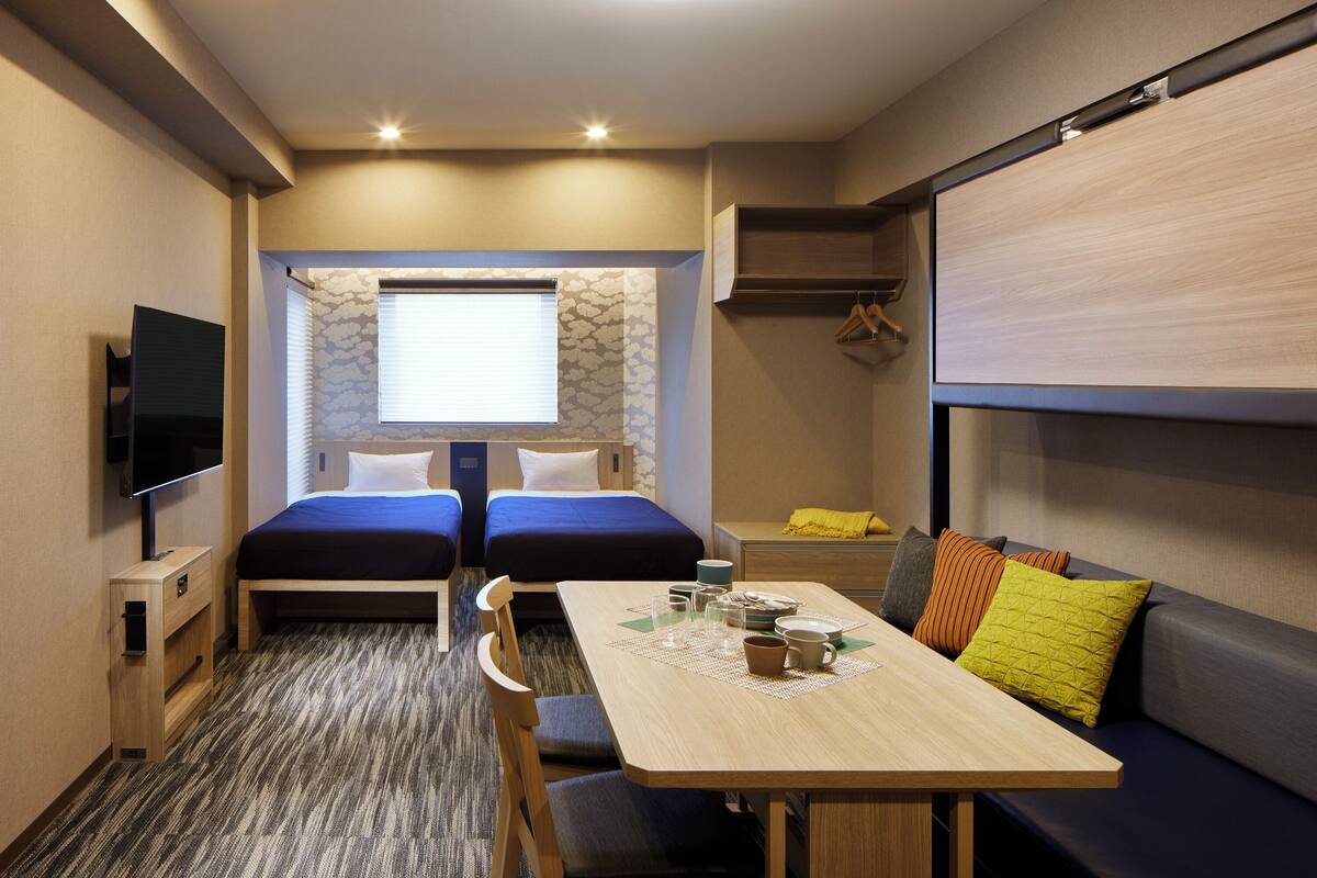 Ein gemütlicher Raum mit Bett, einer Couch, einem Tisch mit Unterlage und einem Fernseher.
