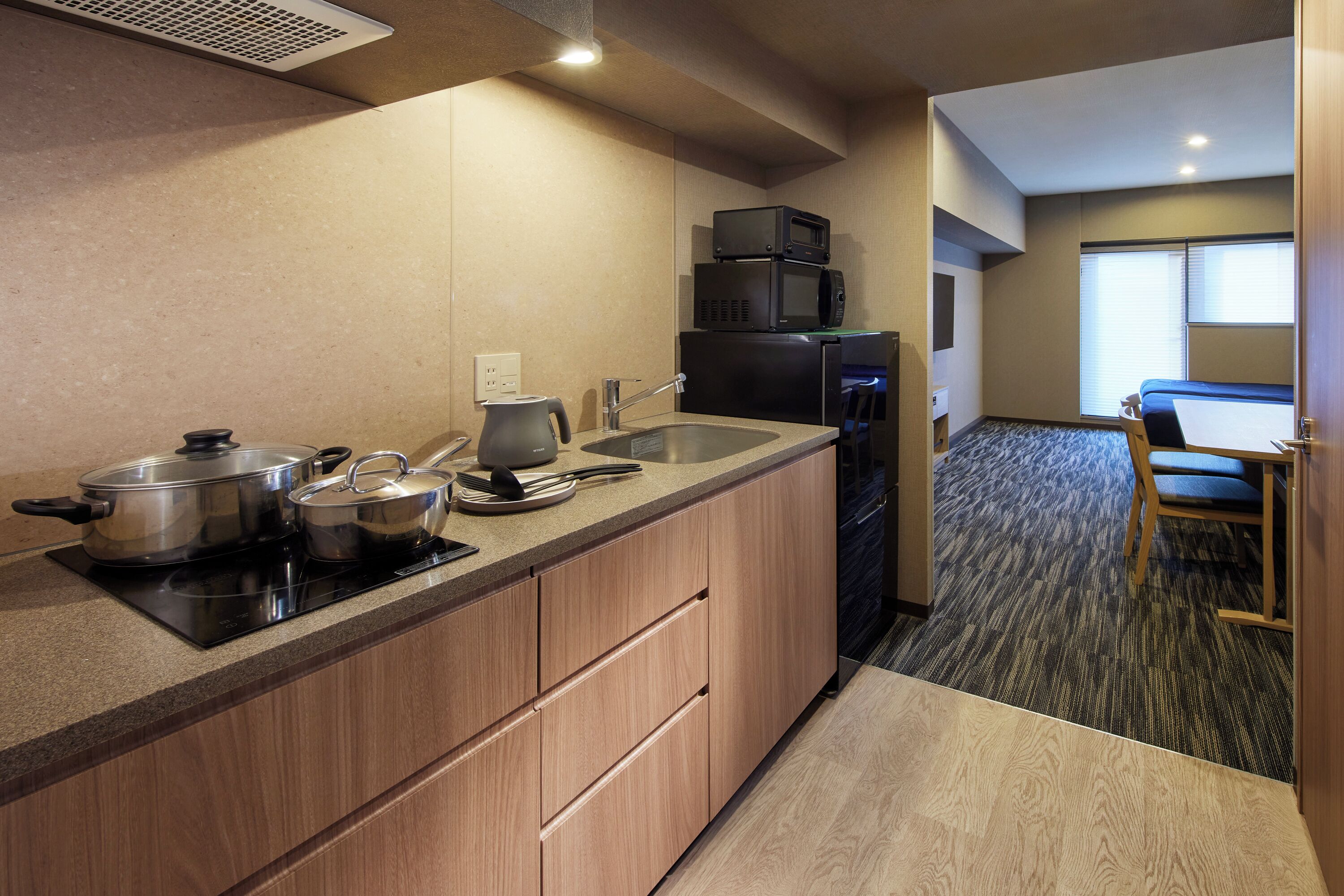 A compact kitchen with a sink, stove, and microwave. There is a dining area with a table and chairs.