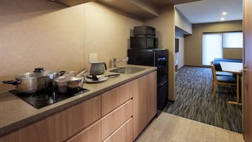 A compact kitchen with a sink, stove, and microwave. There is a dining area with a table and chairs.