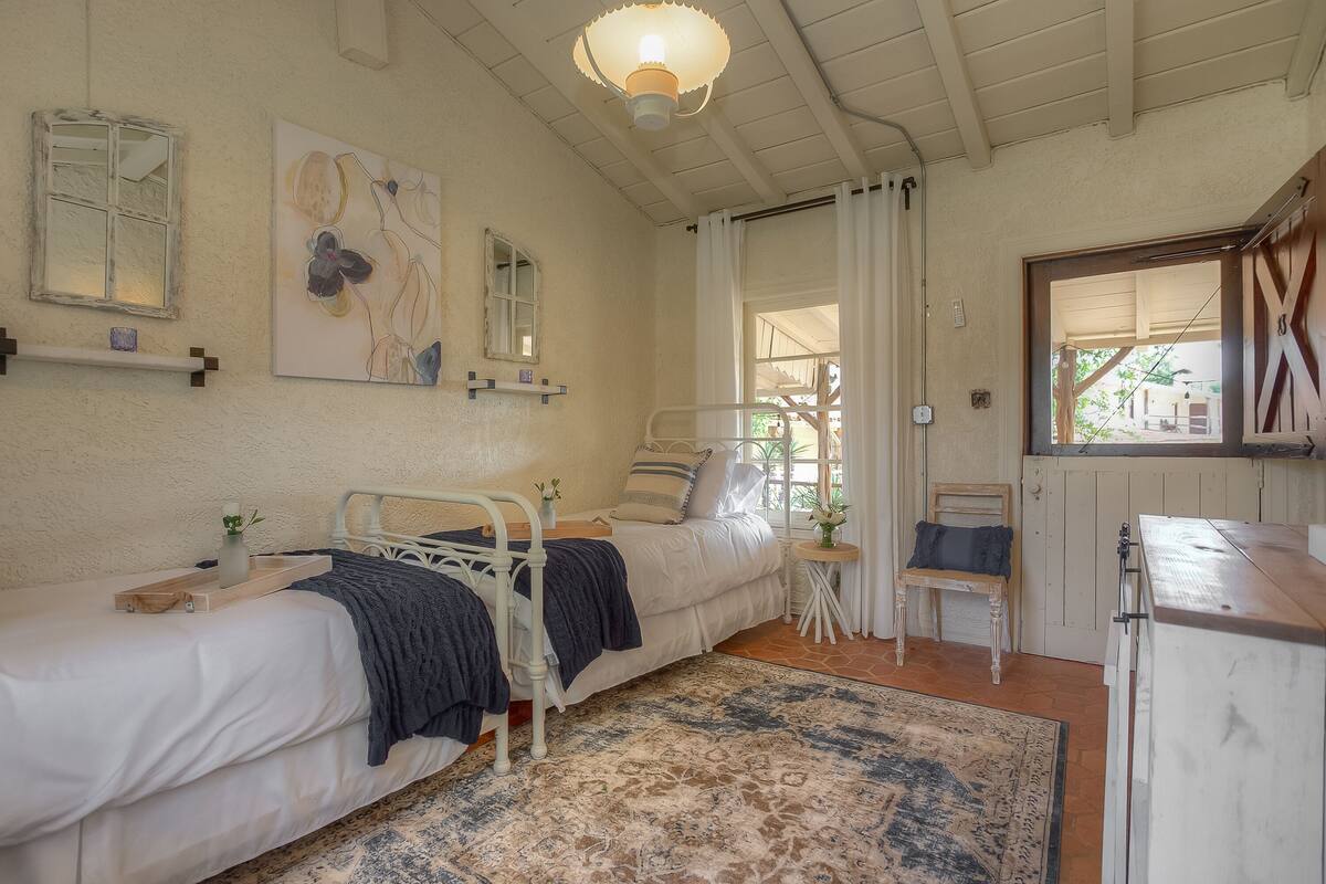 Un dormitorio con dos camas individuales, una mesita de noche, una silla, una pequeña mesa y una lámpara.