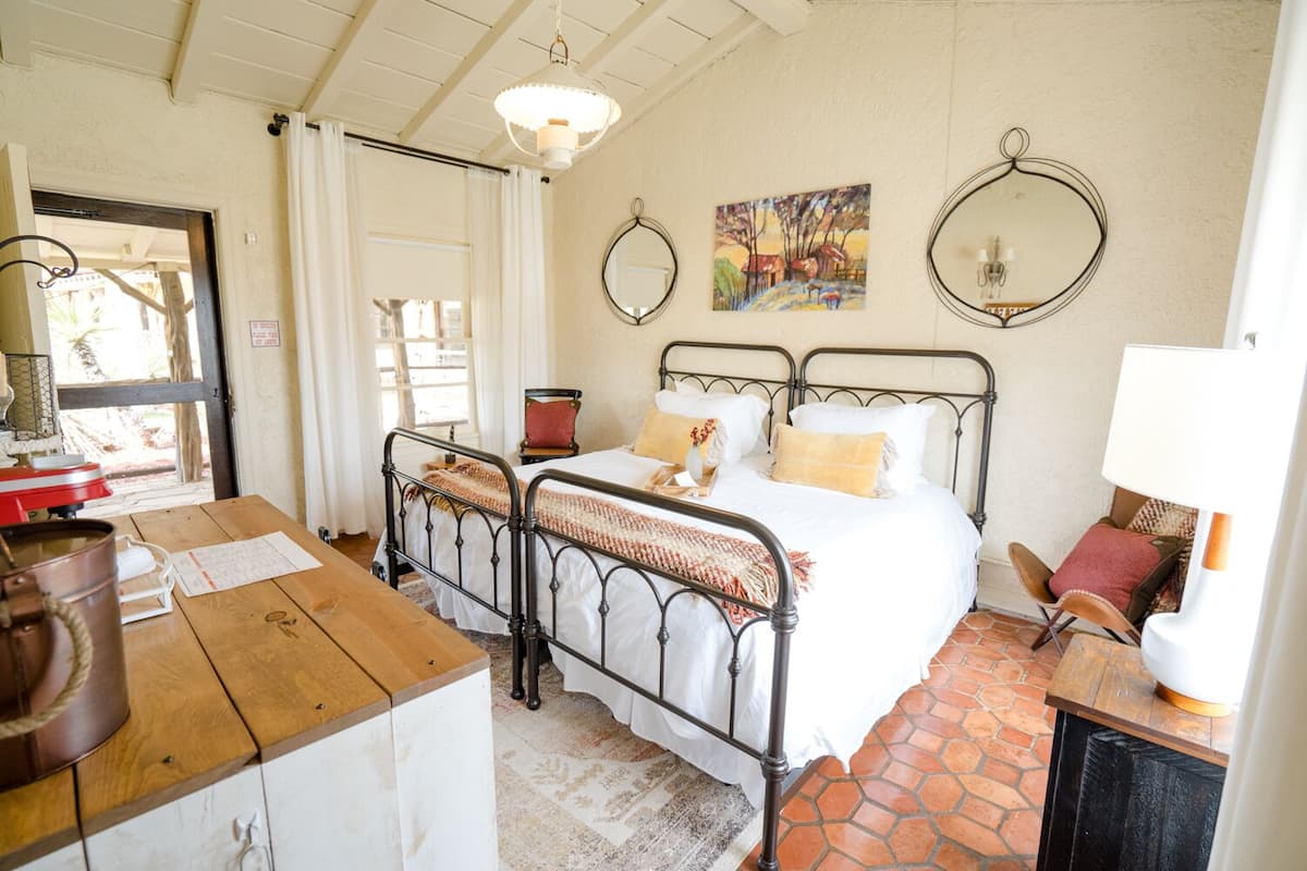 Un dormitorio acogedor con dos camas de estructura metálica, una mesa de madera y una decoración rústica.