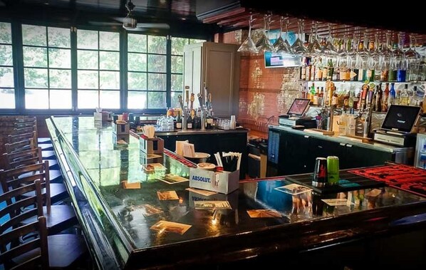 A bar area with a glass counter, bottles, and a computer. - Little Paradise at Lake Conroe (Montgomery)
