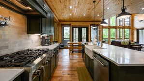 Una cocina moderna con una isla central, techo de madera y ventanas amplias.