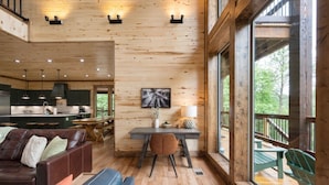 Un interior de cabaña espacioso, con detalles de madera, un comedor y vistas al exterior.