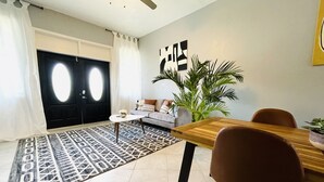 A modern living room with a sofa, coffee table, and a dining table with chairs.