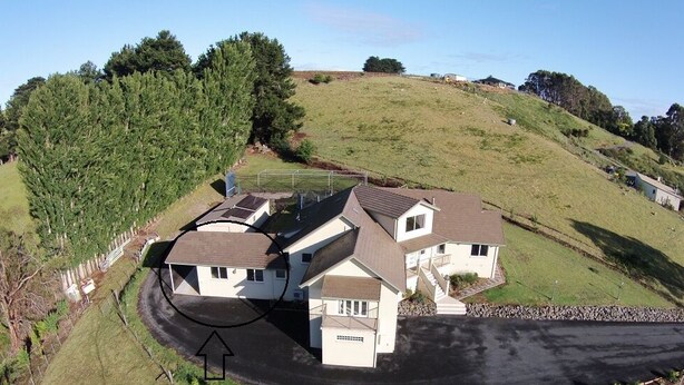 A two-story house with a garage, a driveway, and a hill in the background.