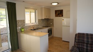 A compact kitchen with a central island, a built-in oven, and a refrigerator.