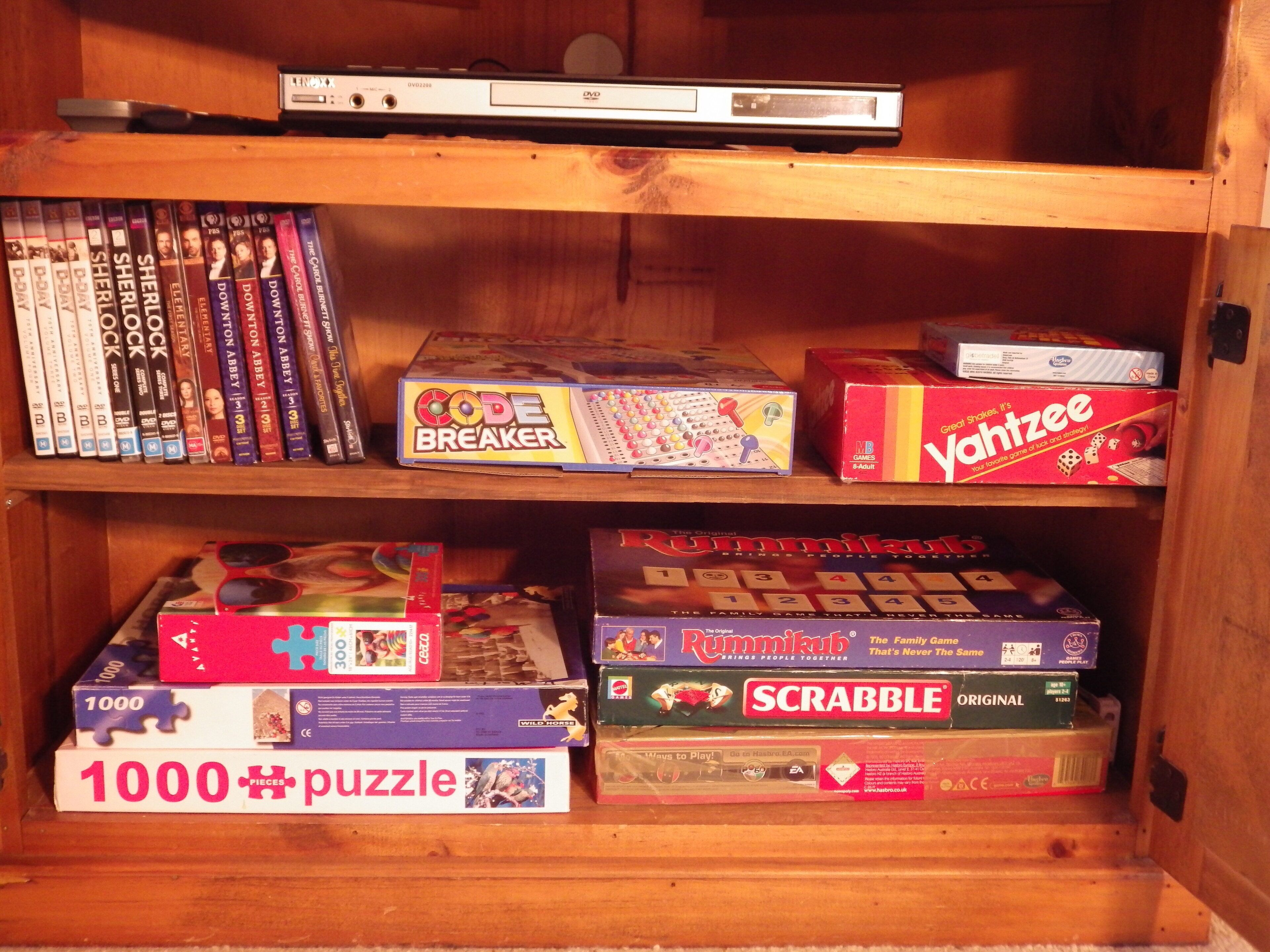 A wooden shelf with various board games and DVDs.