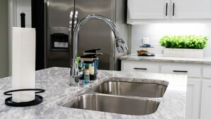 A kitchen with a stainless steel sink, a faucet, and a water dispenser.
