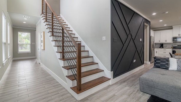 A modern interior with a wooden staircase, a sliding door, and a kitchen area.