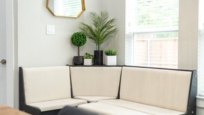 A corner seating area with a cushioned bench, a small potted plant, and a framed mirror on the wall.