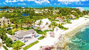 An aerial view of a coastal resort with beachfront properties, clear blue waters, and lush greenery.