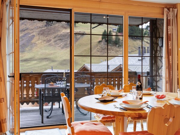 Enjoy a meal with a mountain view from this dining area featuring a wooden table and chairs.