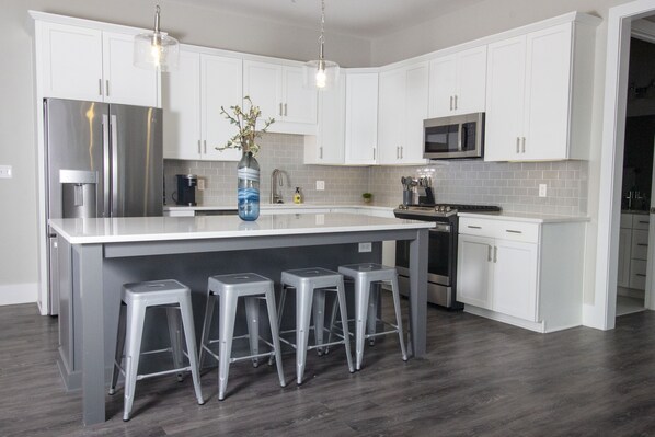A modern kitchen with white cabinets, stainless steel appliances, and a central island with bar stools.