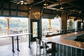 Un restaurante con terraza, ventanas amplias y lámparas colgantes.