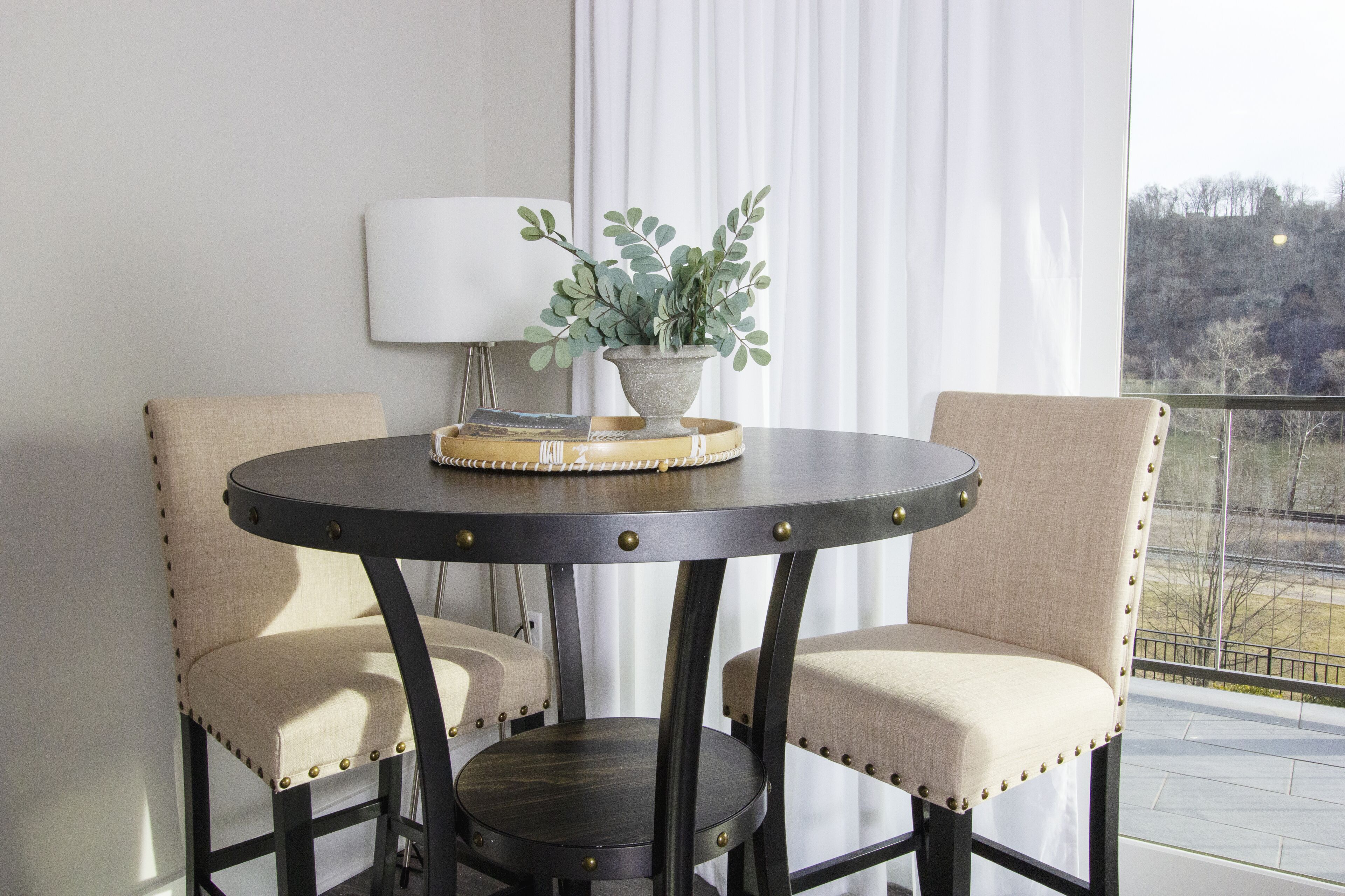 A round table with two upholstered chairs, a potted plant, and a decorative tray.