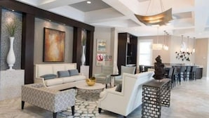 Una sala moderna con un sofá, sillones y una mesa de centro. Hay una zona de comedor con una barra y sillas.