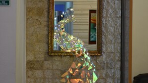 Eine Steinsäule mit einem gerahmten Spiegel, der eine dekorative Lichtskulptur reflektiert.