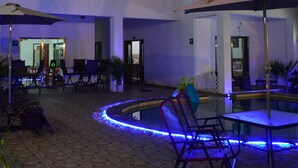 Ein mehrstöckiges Hotel mit Außenbereichen, einem Pool und einem gut beleuchteten Atrium.