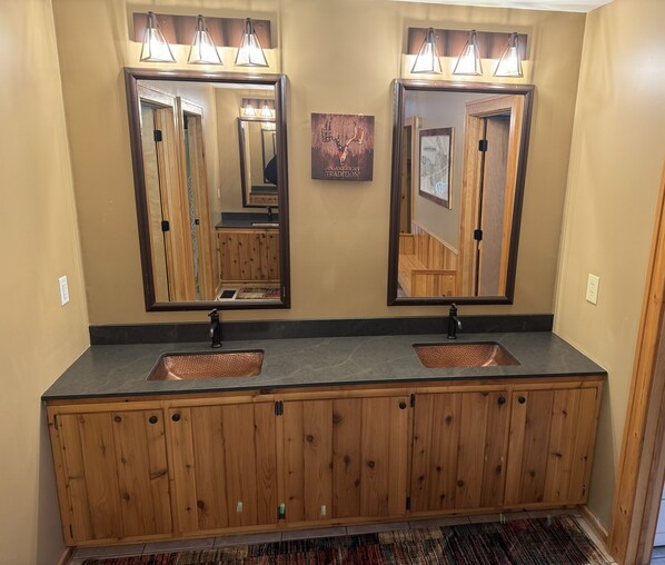 Une salle de bain avec deux lavabos, des meubles en bois et un miroir avec éclairage intégré.