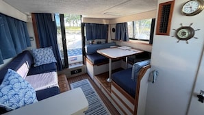 Interior compacto de una autocaravana con una cama, un pequeño comedor y una kitchenette.