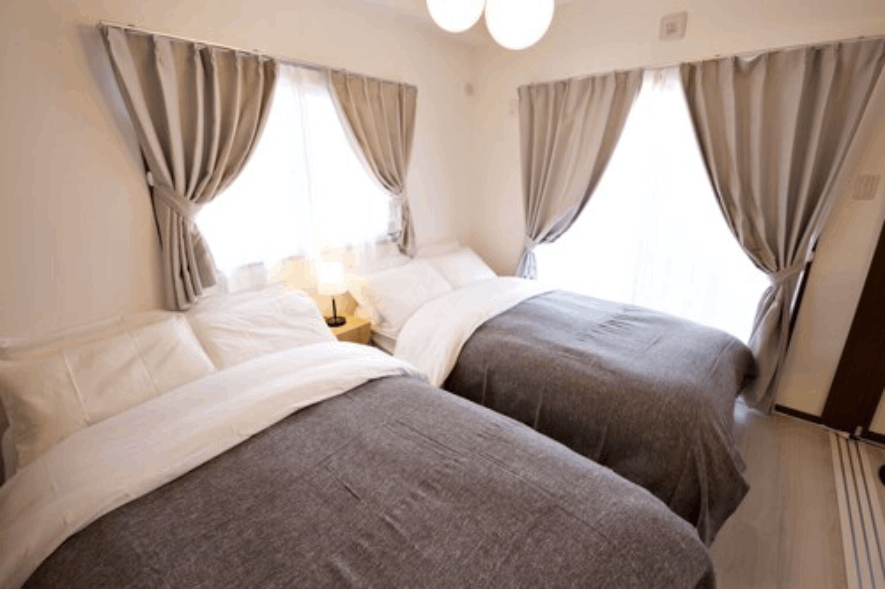 A hotel room with two beds, a nightstand, and curtains.