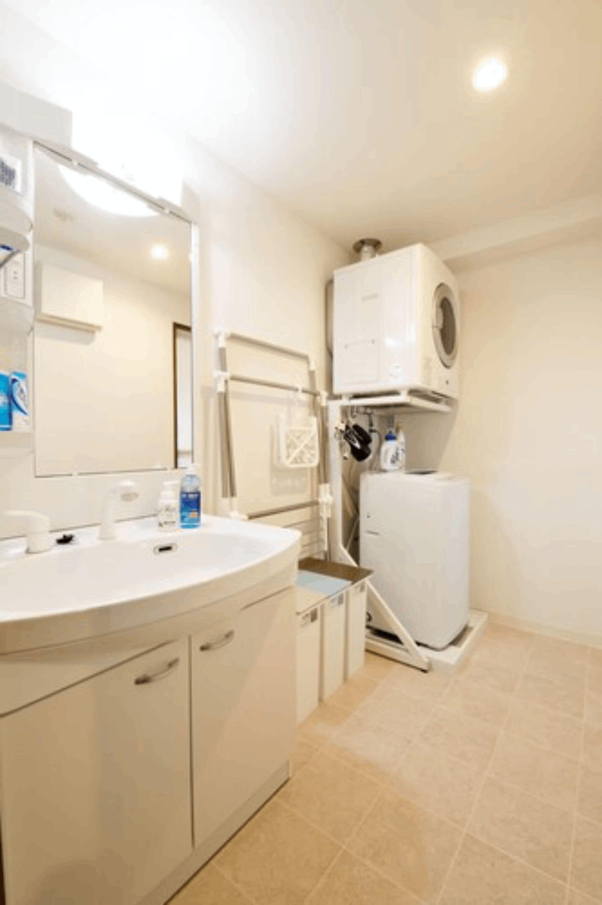 A bathroom with a white sink, mirror, and a built-in washing machine.