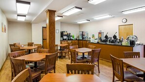 Een restaurant met houten tafels en stoelen, een balie met wafelijzers en een prullenbak.
