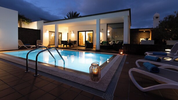 A modern outdoor pool area with lounge chairs and a covered seating area. - Villas Mamma Mia Sleeps 6 with Pool (Playa Blanca)