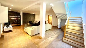 A spacious living area with a modern design, featuring a staircase, a fireplace, and a bookshelf. - Villas Mamma Mia Sleeps 6 with Pool (Playa Blanca)