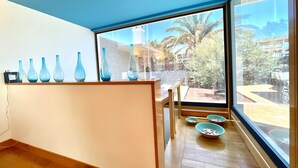 A room with a large window, a wooden floor, and a shelf with blue vases. - Villas Mamma Mia Sleeps 6 with Pool (Playa Blanca)