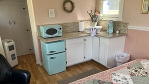Een kleine keuken met een oude magnetron, een koelkast en een spoelbak.