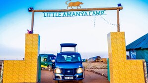 Un véhicule entre dans un camp où un panneau indique : « Little Amanyacamp ».