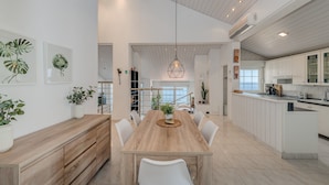 A modern kitchen with white cabinets, a wooden dining table, and a hanging light fixture. - Luxury apt w shared pool,3 balconies and terrace (Omis)