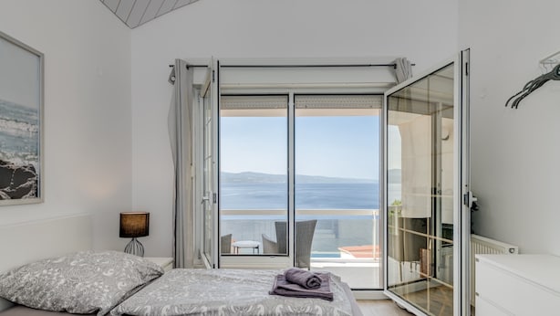 A bedroom with a large sliding glass door leading to a balcony with a view of the sea. - Luxury apt w shared pool,3 balconies and terrace (Omis)