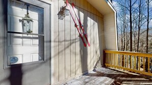 A wooden porch with a yellow railing, a welcome sign, and a pair of skis leaning against the wall. - Warm & Inviting Ski Getaway w/ a Full Kitchen, Fireplace, & Furnished Deck (Sugar Mountain)