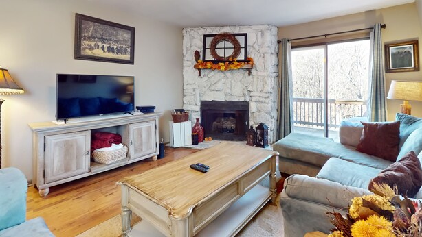 A living room with a stone fireplace, a television, and a sofa. - Warm & Inviting Ski Getaway w/ a Full Kitchen, Fireplace, & Furnished Deck (Sugar Mountain)