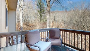A balcony with two chairs and a table, overlooking a forested area. - Warm & Inviting Ski Getaway w/ a Full Kitchen, Fireplace, & Furnished Deck (Sugar Mountain)