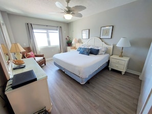 A neatly arranged bedroom with a bed, bedside tables, a desk, and a ceiling fan.
