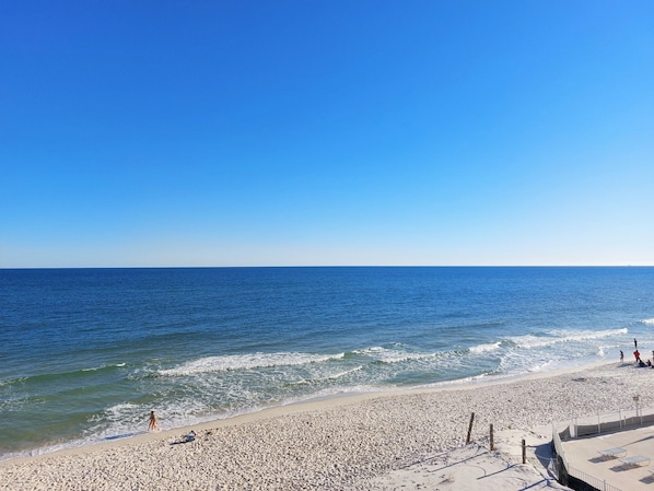 A beach with a clear sky, calm sea, and a sandy shore.