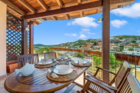 A wooden table set for dining with a view of a hillside town.