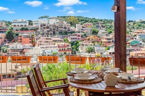 Un balcón con una mesa lista para comer, con vistas a una colina llena de edificios de colores.