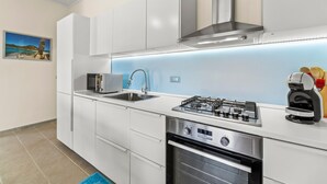 Een moderne keuken met witte kastjes, een roestvrijstalen fornuis, een ingebouwde oven en een blauwe achterwand.