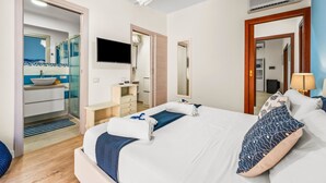 Een hotelkamer met een bed, een televisie, een badkamer met een wastafel en een spiegel.