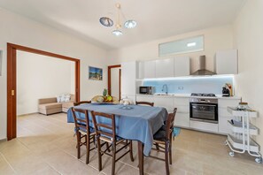 A modern kitchen with white cabinets, a microwave, an oven, and a dining area with a table and chairs.