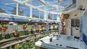 Un bain à remous avec un mur en mosaïque, un plafond en verre et des plantes en pot.
