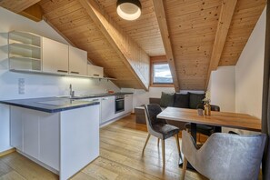 Una cucina moderna con mobili bianchi, soffitto in legno e zona pranzo con tavolo e sedie.