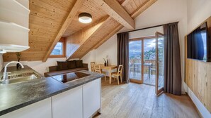 A modern kitchen with a wooden ceiling, a dining area with a table and chairs, and a sliding glass door leading to an outdoor balcony. - Luxury Apartment "Weißhorn" with Mountain View and private Steam Sauna (Deutschnofen)