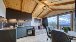 A modern kitchen with wooden beams, a dining area with a view, and a cozy seating space.